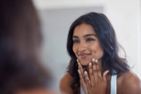 young South Asian woman looking at her face in the mirror
