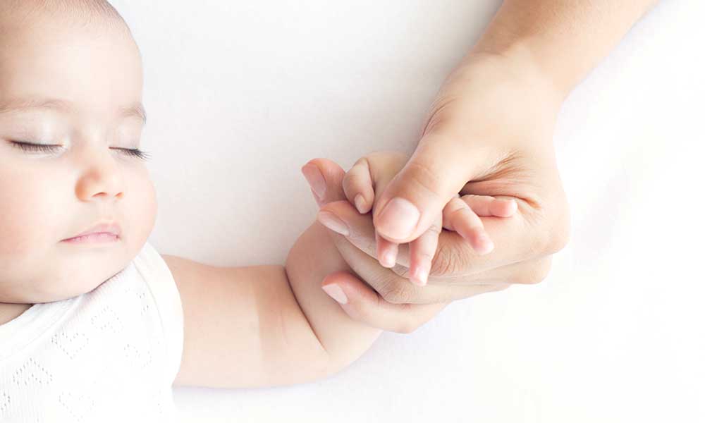 a baby holding an adult's hand