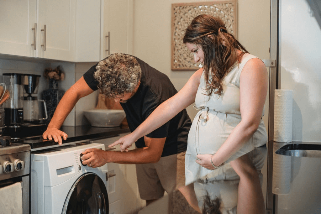 a pregnant lady and her husband looking at the washing machine