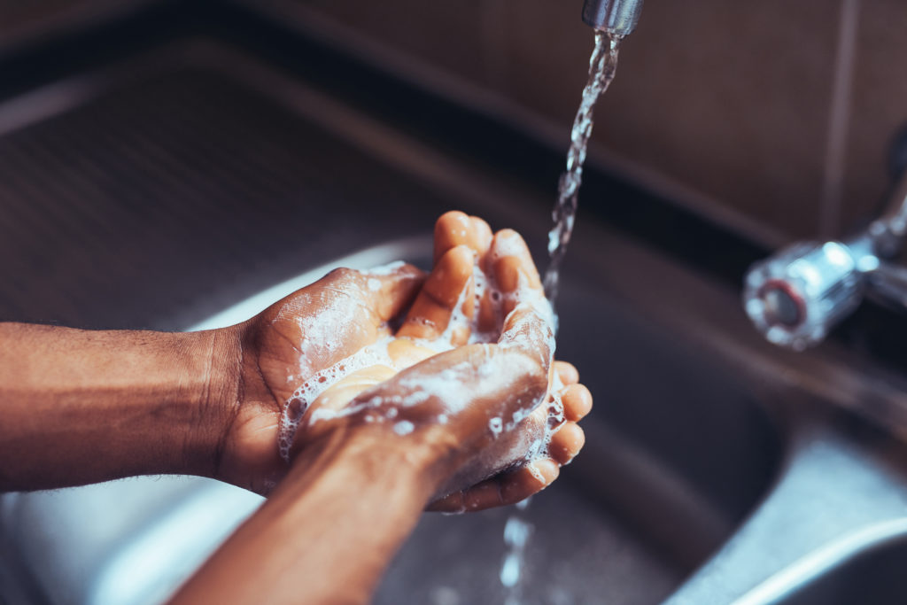 Image of someone with a skin condition 
washing their hands with water from a tap