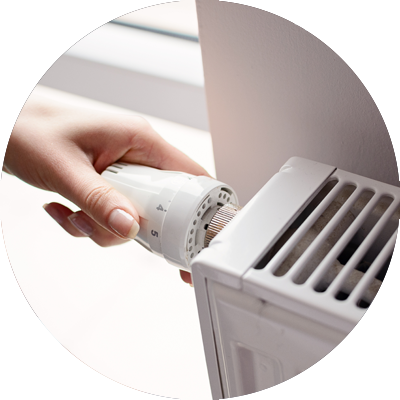 Woman hand turning a radiator thermostat down
