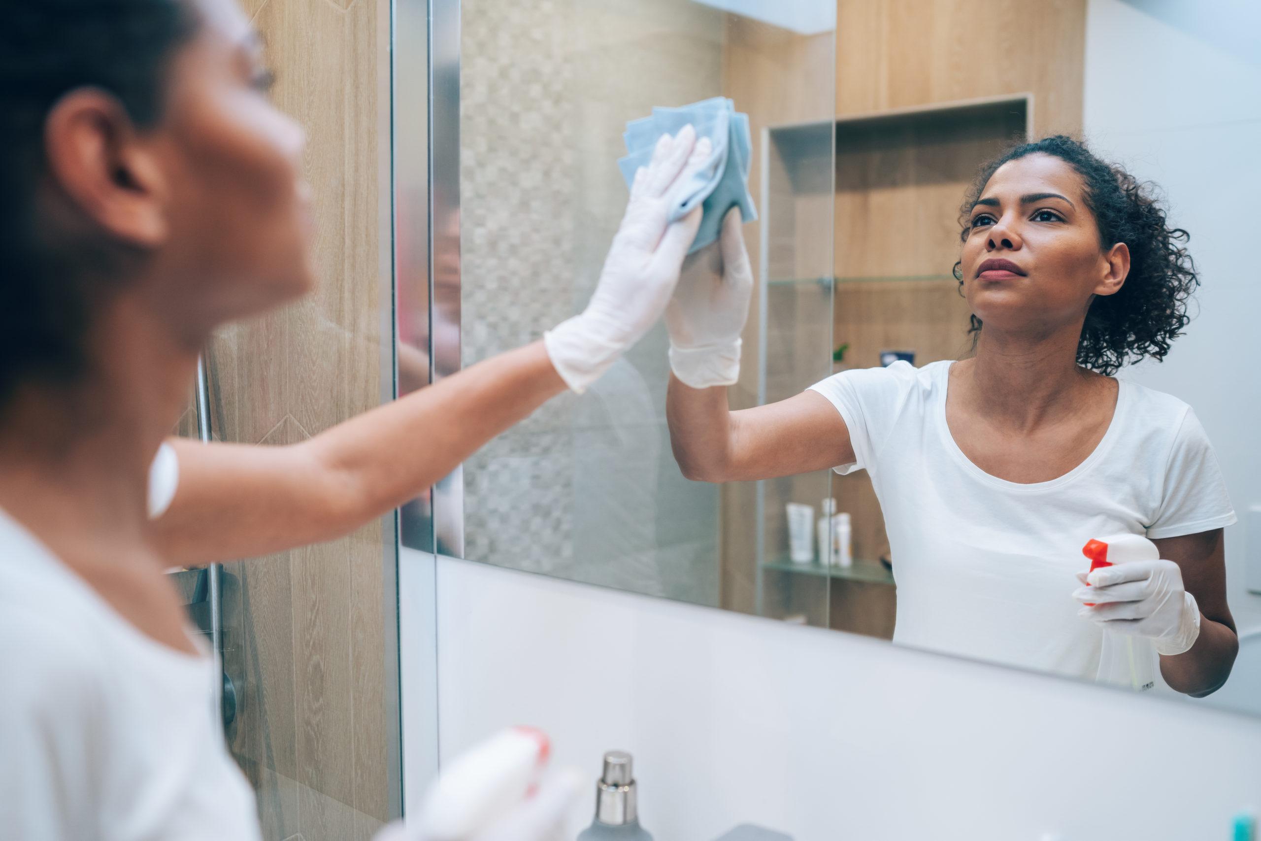 Woman cleaning a mirror of water marks