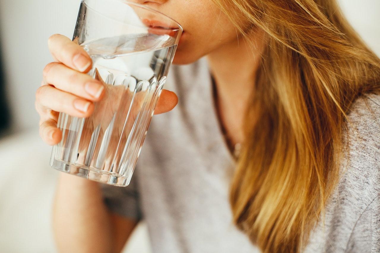 Woman drinking a glass of soft water)