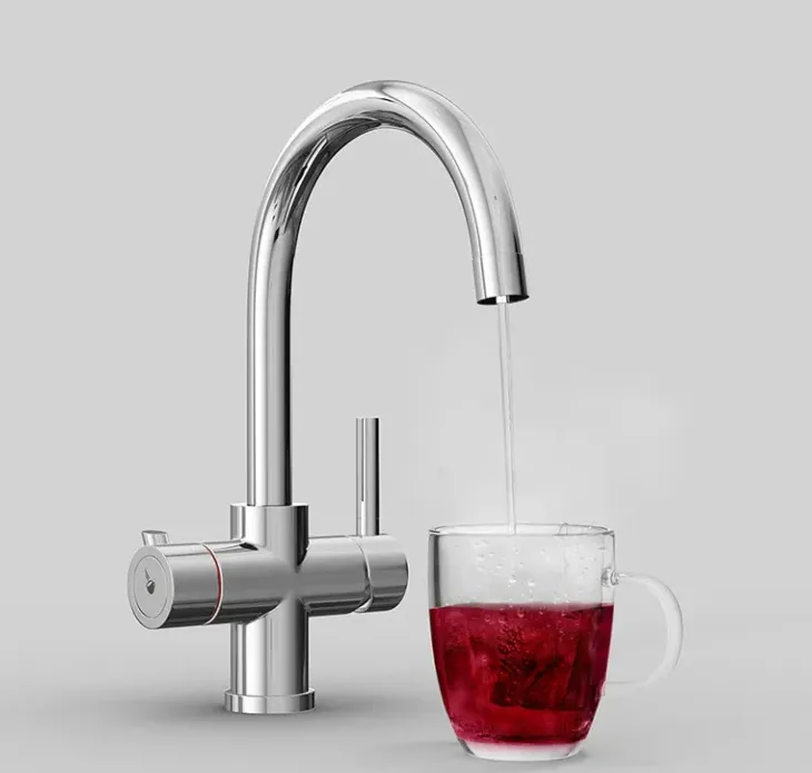A sleek chrome faucet pours clear water into a transparent glass filled with red liquid, set against a gray background.